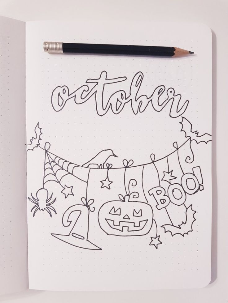 a notebook with the word october written on it and halloween decorations hanging from a line