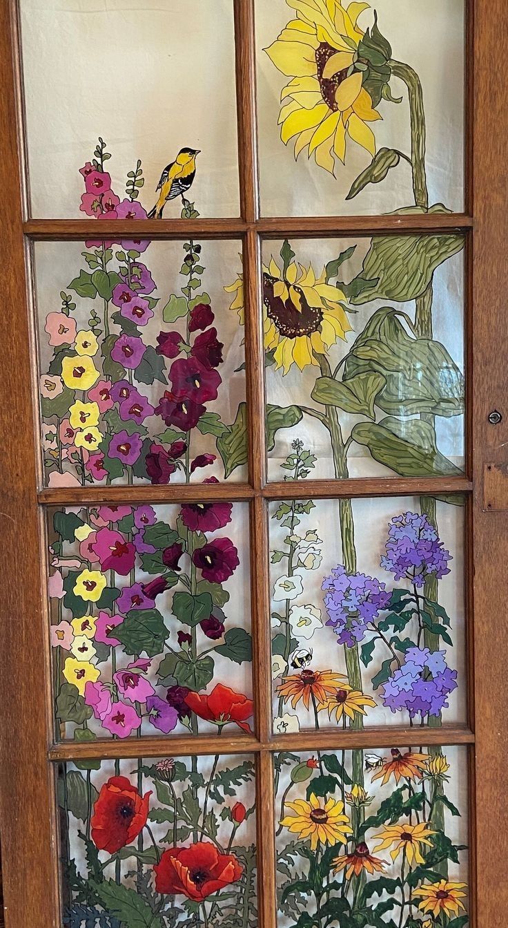 a window with flowers painted on the glass and in front of it is a wooden frame