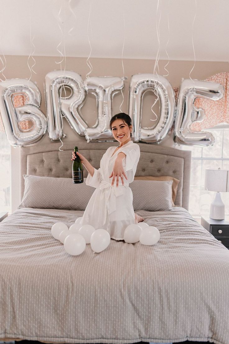 a woman sitting on top of a bed in front of balloons and the word bridal