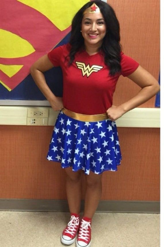 a woman wearing a red shirt and blue skirt with white stars on it, standing in front of a superman poster