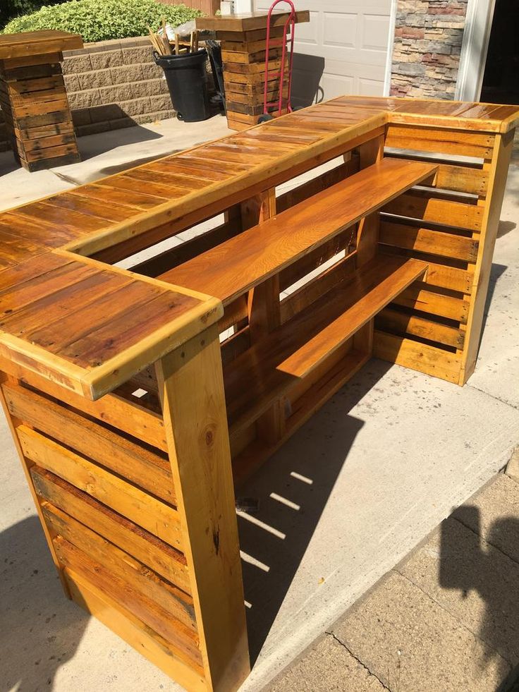 a wooden bench sitting on top of a sidewalk next to a wall and potted planter