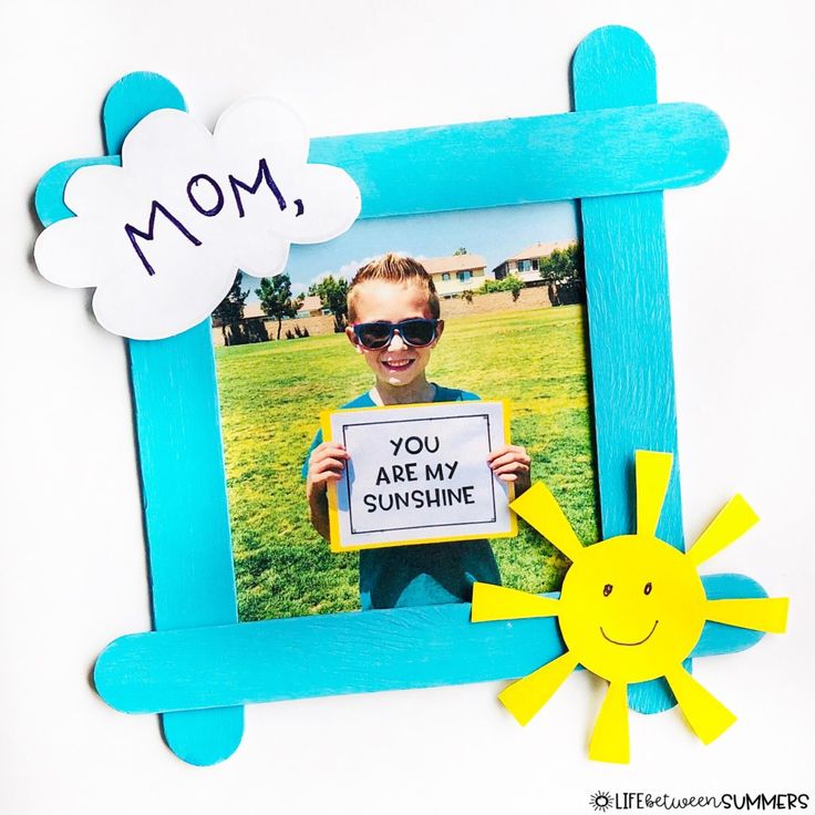 a child holding up a photo frame with the words mom and you are my sunshine written on it