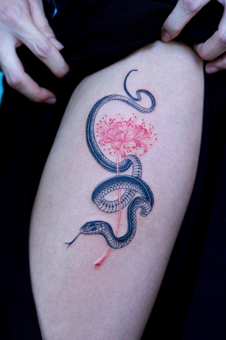 a woman's thigh with a snake and flower tattoo on it