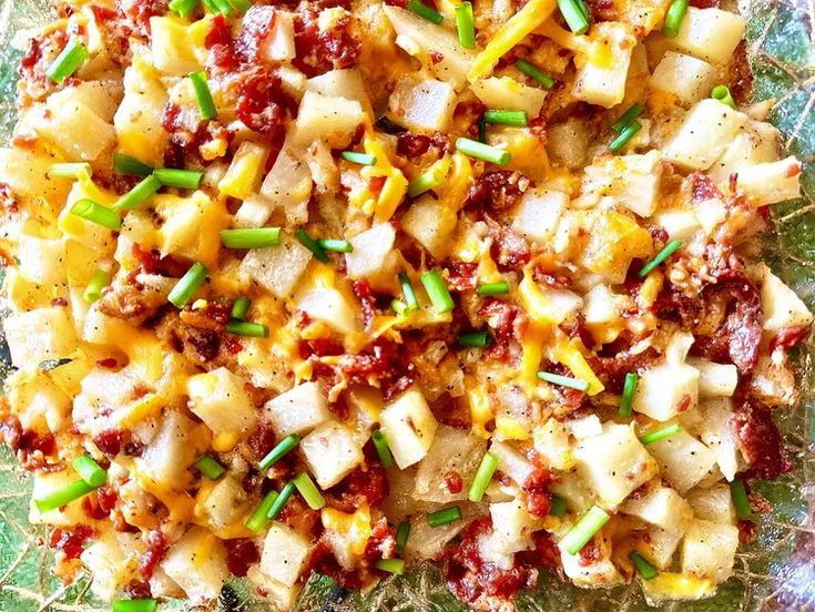 a close up view of some food on a glass plate with green onions and cheese