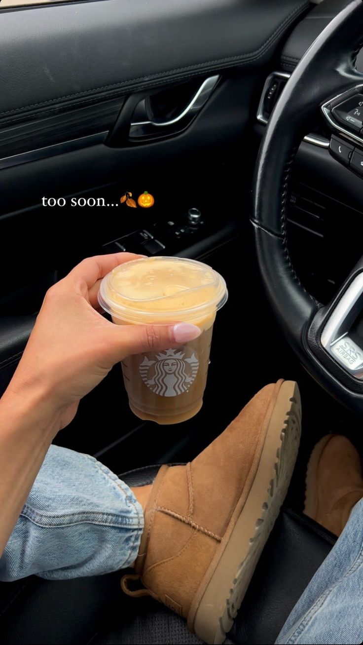 a person holding a cup of coffee while sitting in a car