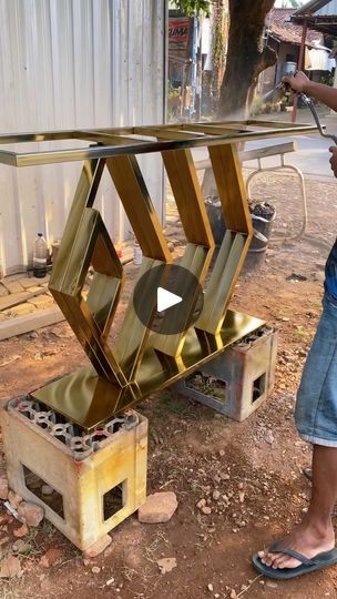 a person standing next to a metal object on top of a wooden table with holes in it