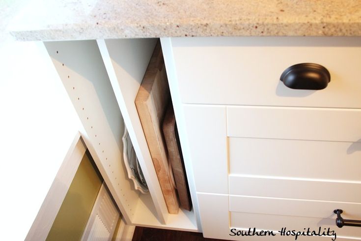 an open cabinet door in a kitchen next to a counter with drawers and cupboards