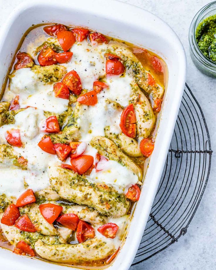 a casserole dish with chicken, tomatoes and pesto