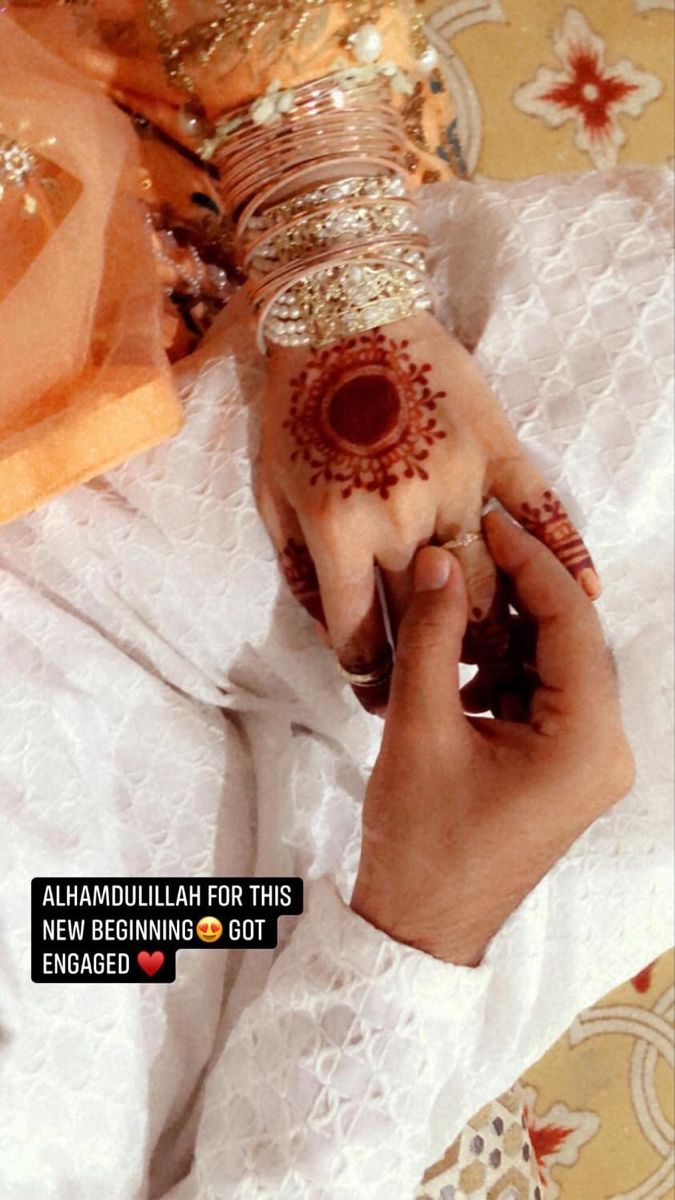 a person with henna on their hand and bracelets around her wrist holding something in the other hand