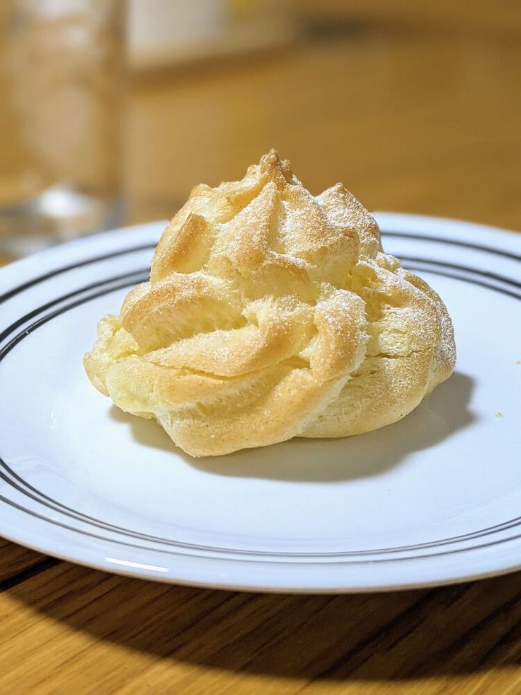 a white plate topped with a pastry on top of a wooden table