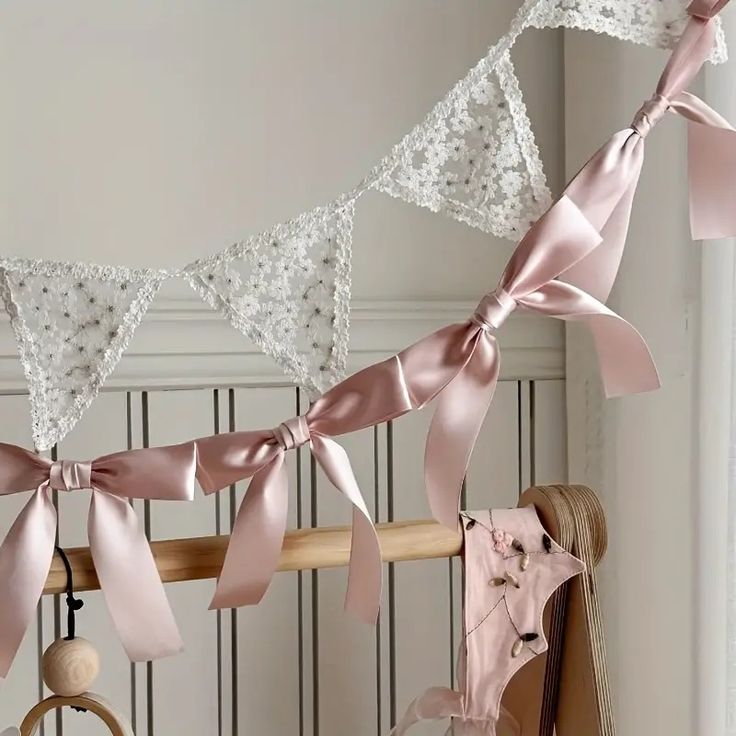 pink and white bows hanging from a wooden rail in front of a wall with other items on it