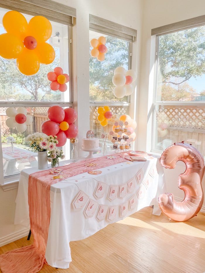 a table with balloons and other decorations in the window sill at a birthday party