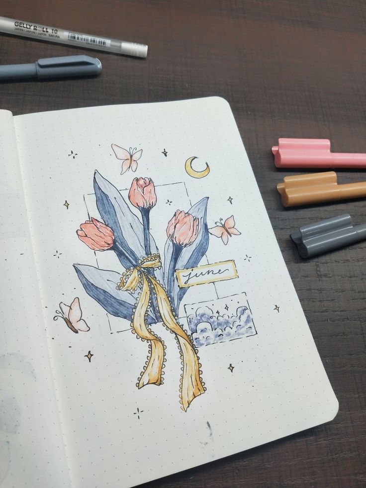 an open notebook with flowers and butterflies drawn on it next to some crayons