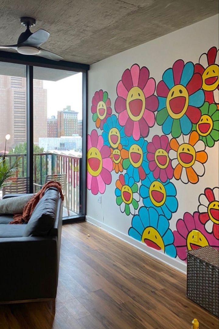 a living room filled with furniture next to a large painting on the wall behind a window