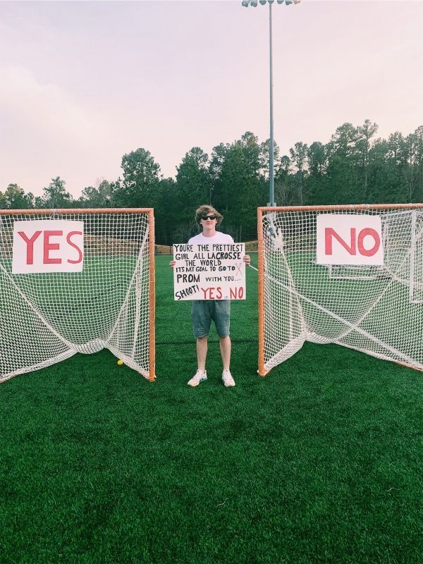 a man standing in front of two soccer goal posts holding a sign that says yes and no