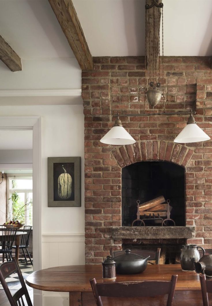 a brick fireplace in a dining room with wooden chairs and a table next to it