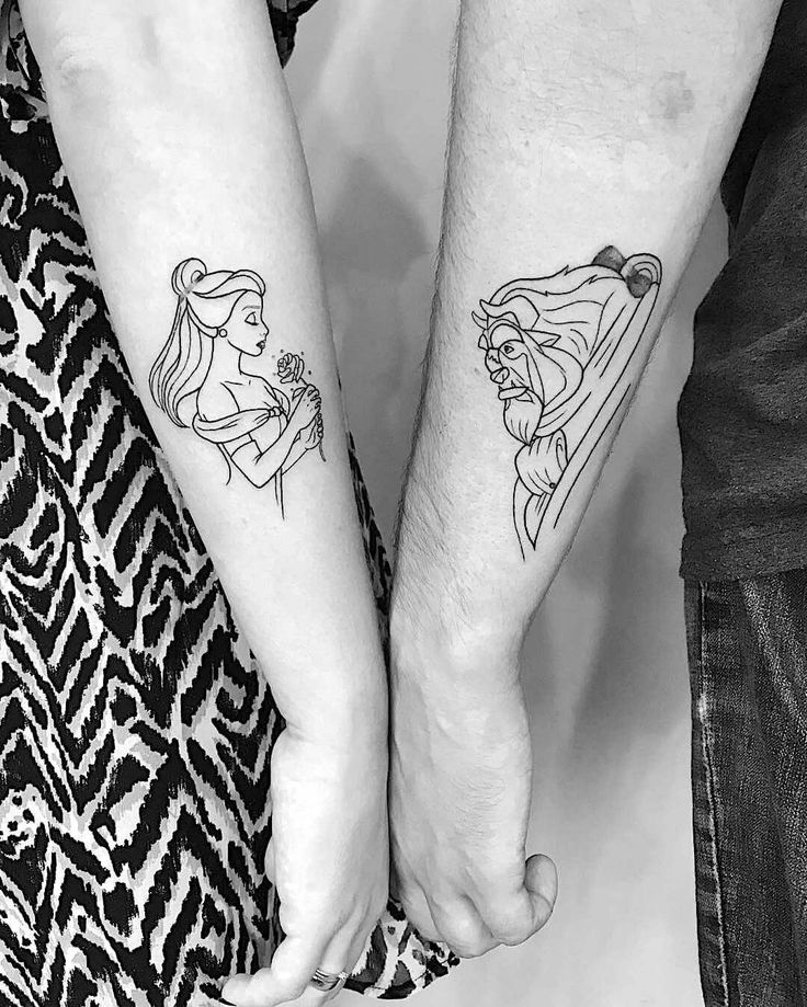 two people holding hands with disney tattoos on their arms and wrist, both wearing matching outfits