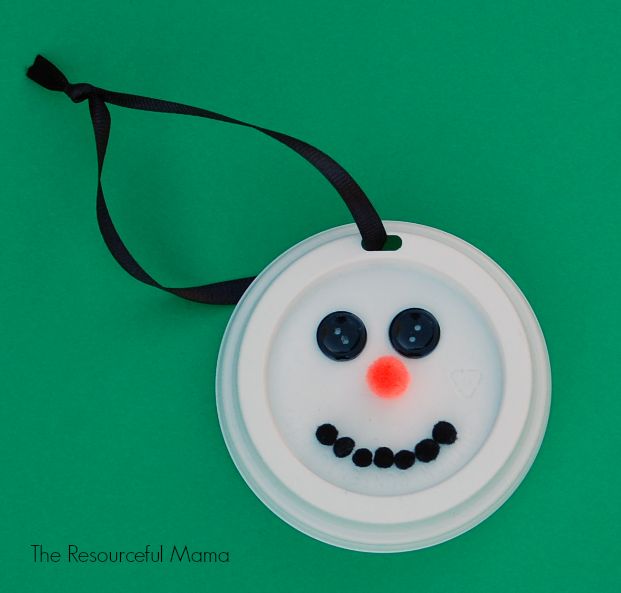 a snowman ornament is hanging on a green surface with a black ribbon