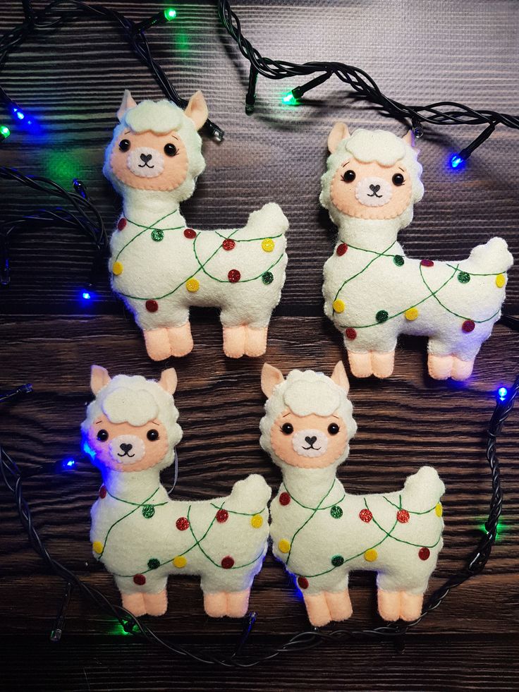 stuffed llamas are adorned with christmas lights on a wooden table in front of some string lights