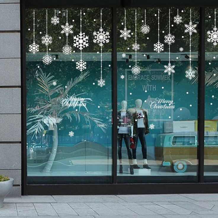 a store front with snowflakes hanging from the windows and decorations on the outside