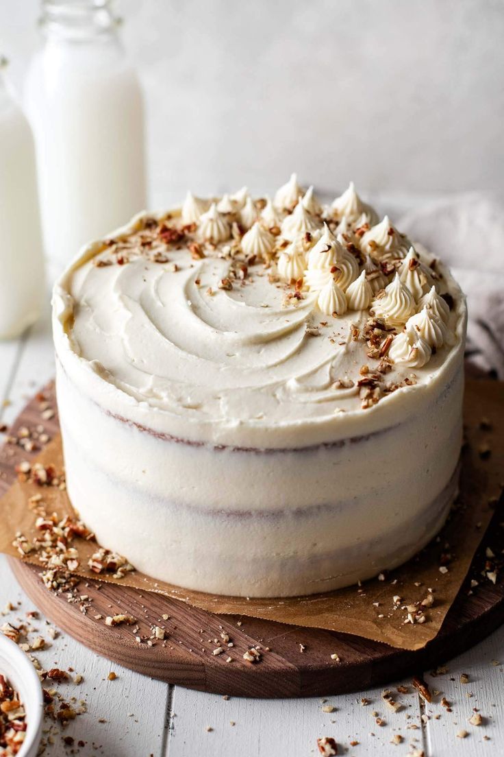 a cake with white frosting and sprinkles sitting on a wooden board