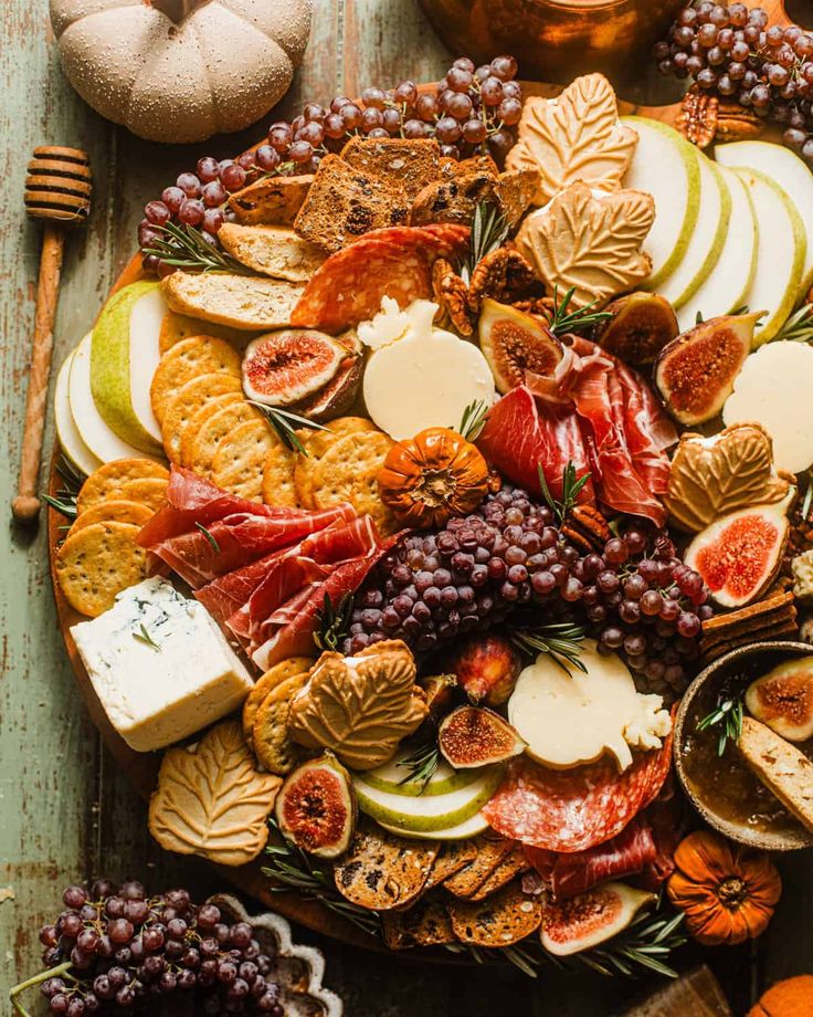 an assortment of cheeses, crackers and fruits on a platter