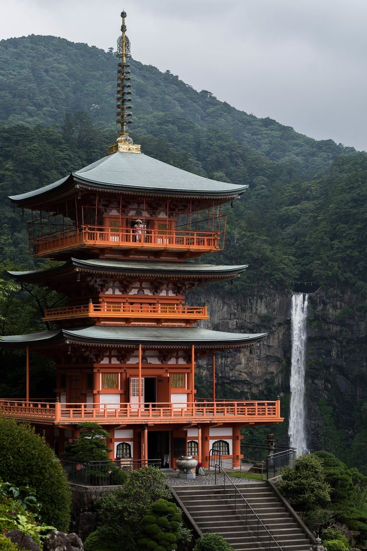 a tall red building sitting next to a waterfall