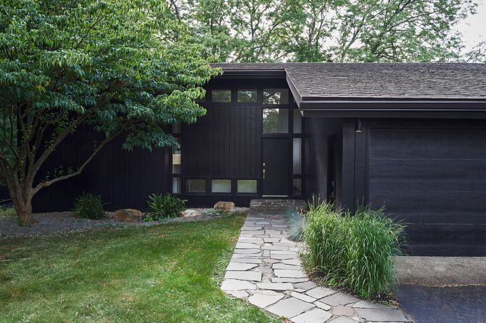 a black house with green grass and trees