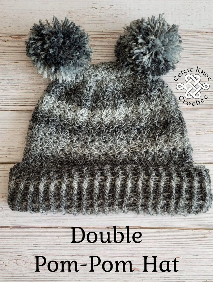 the double pom - pom hat is knitted in grey and white yarn