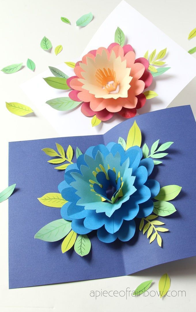 two cards with paper flowers on them, one is blue and the other is pink