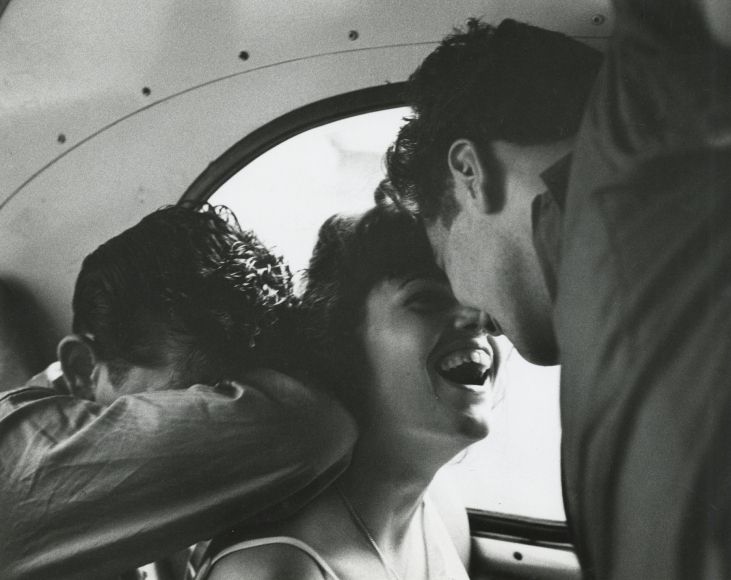 a man and woman are laughing in the back of a car while another person looks on