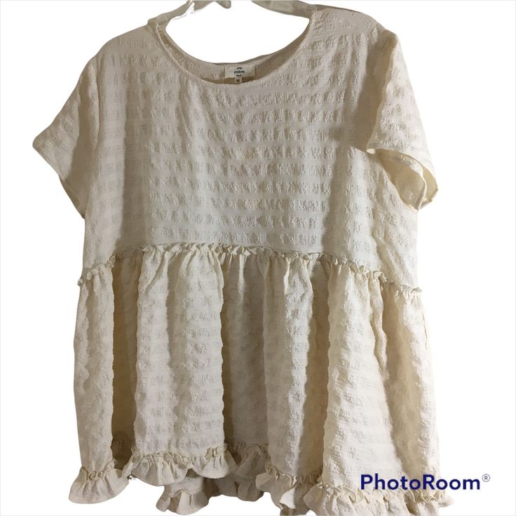 40 Percent Poly And 60 Rayon. Length Measures 26 Inches And Bust Measures 23 Inches Across. Ro82 Fitted Off White Tops With Ruffles, Flowy Tiered Ruffled Tops, Summer Off White Ruffled Blouse, Off White Fitted Ruffle Tops, White Tiered Tops For Summer, White Tiered Summer Top, Cream Flowy Short Sleeve Tops, Flowy Cream Short Sleeve Tops, White Tiered Top With Ruffle Hem