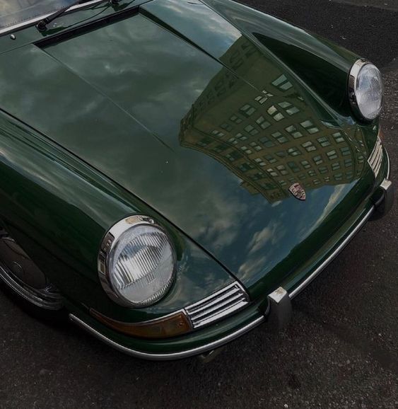 a green sports car parked in a parking lot with its hood up and headlight on