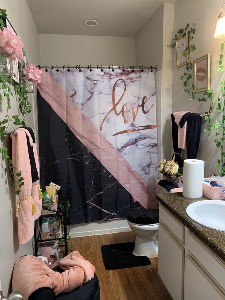 a bathroom decorated in pink, black and white with the word love painted on the shower curtain