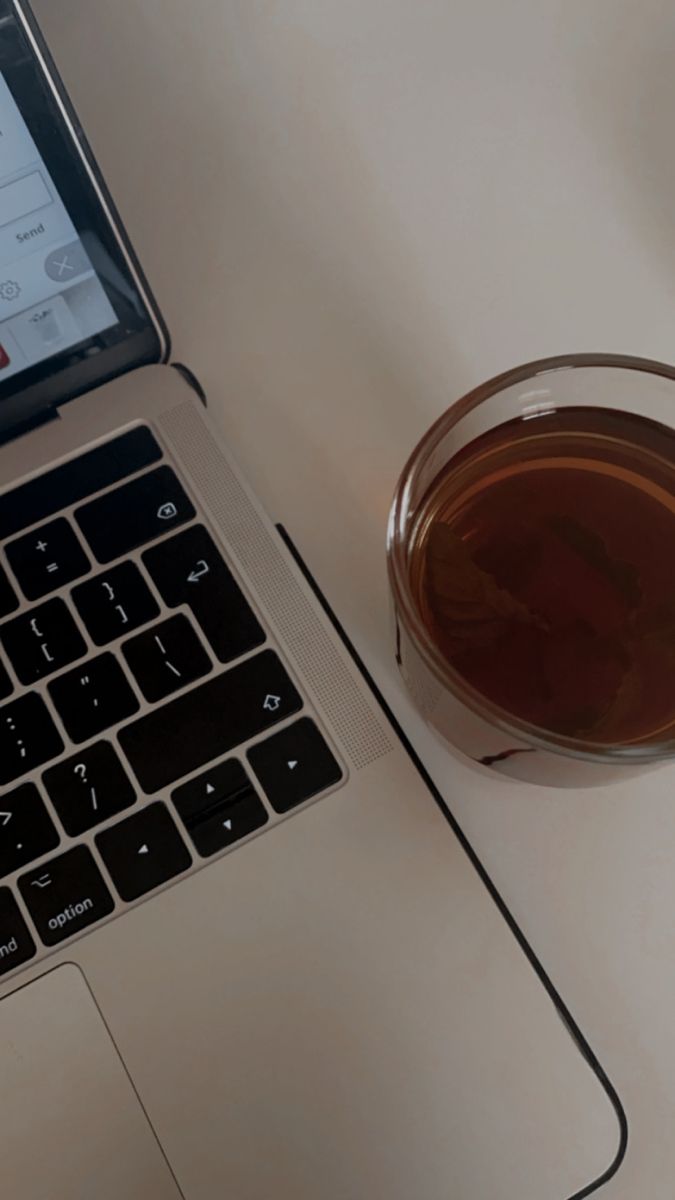 an open laptop computer sitting on top of a white table next to a cup of coffee