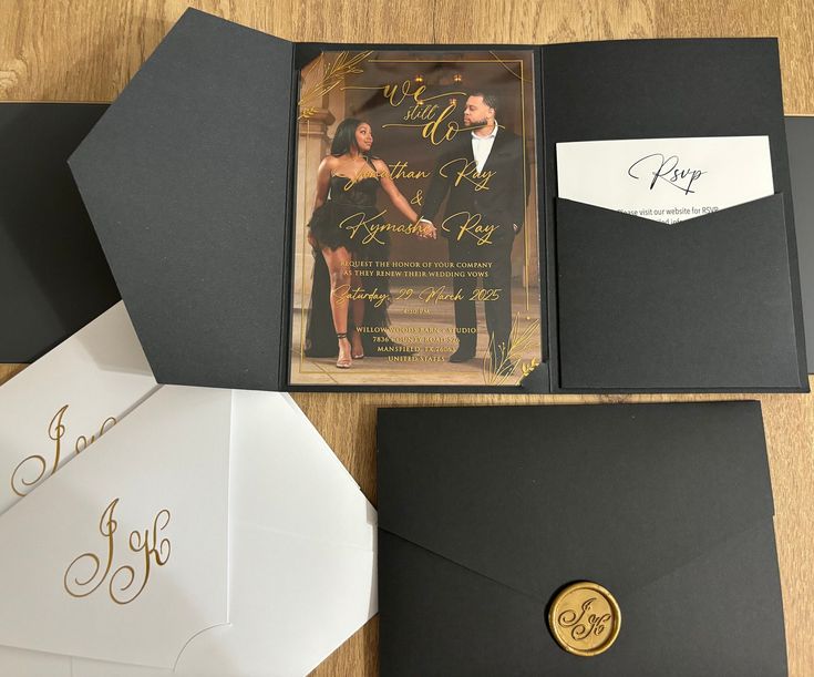 an open black and white wedding card with gold lettering