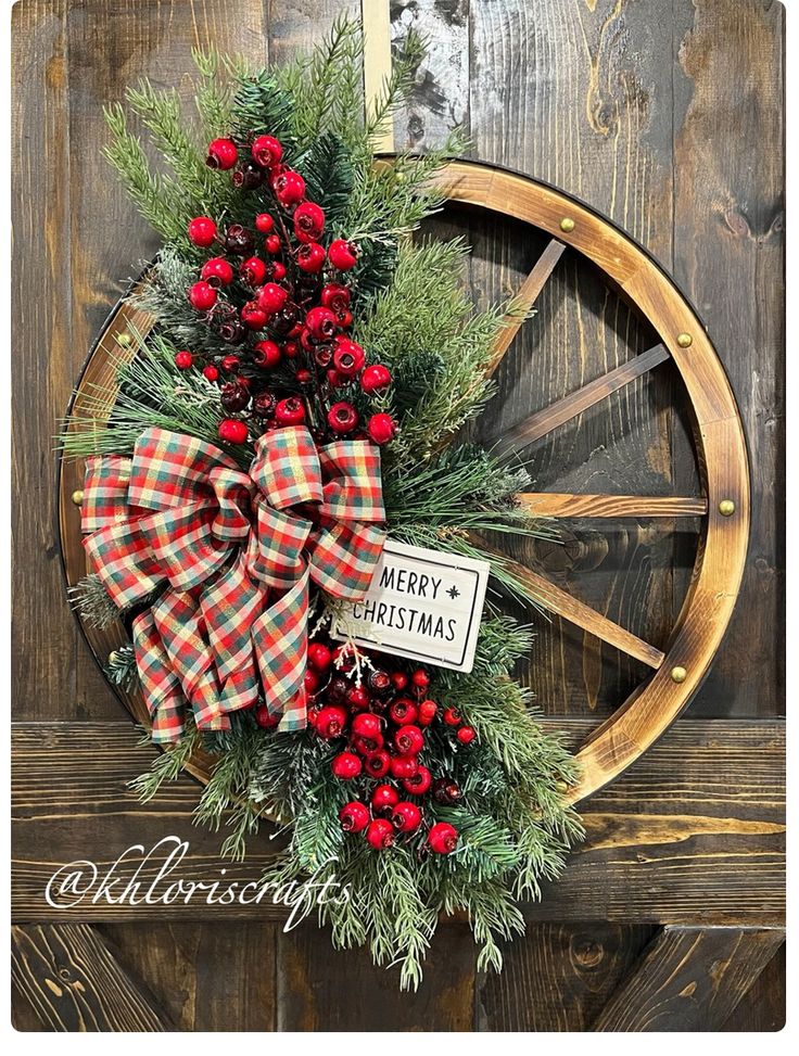 a christmas wreath with red berries and pine cones on a wagon wheel door hanger