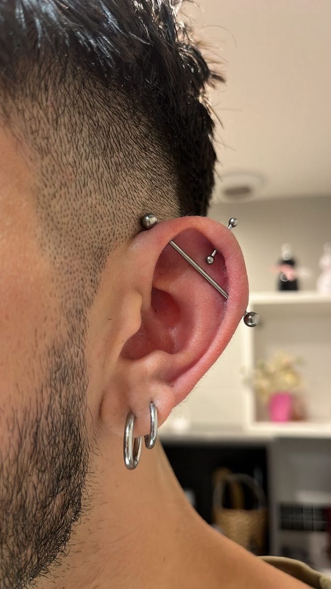 a man with piercings on his ears is looking at the camera while wearing a pair of hoop earrings