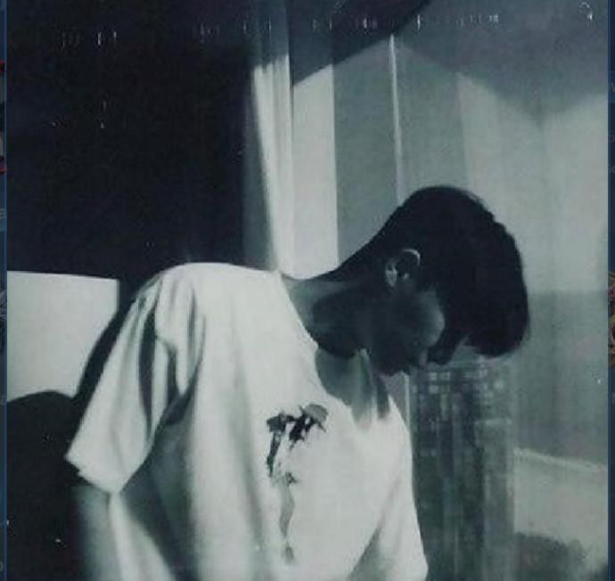 black and white photograph of a person leaning against a wall with their head in his hands