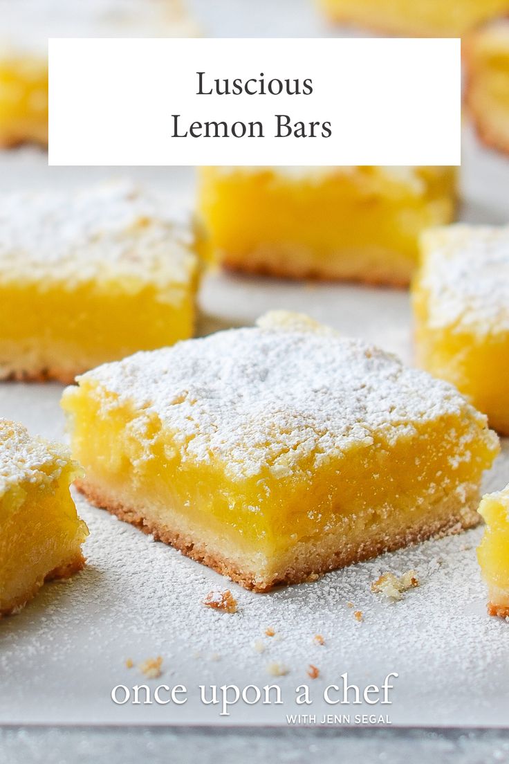 several pieces of lemon bars sitting on top of a baking sheet covered in powdered sugar