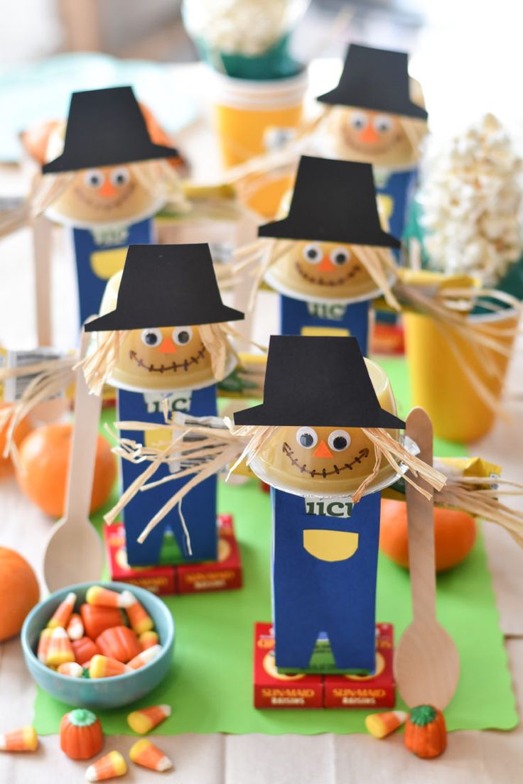 some paper scarecrows are sitting on a table with candy and candies in front of them