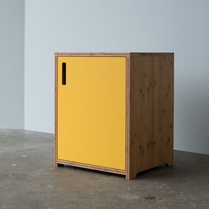 a yellow cabinet sitting on top of a cement floor next to a white wall in an empty room