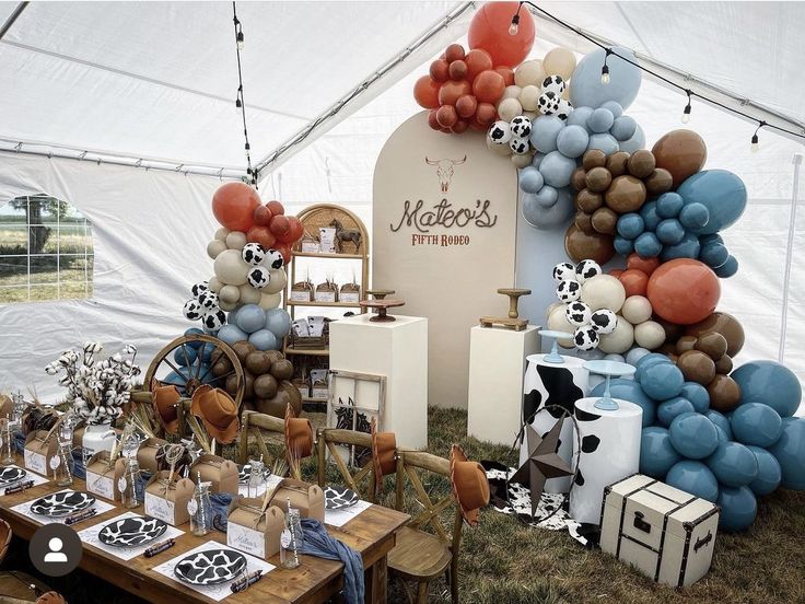 an outdoor party with balloons and decorations on the table, including cow - print napkins