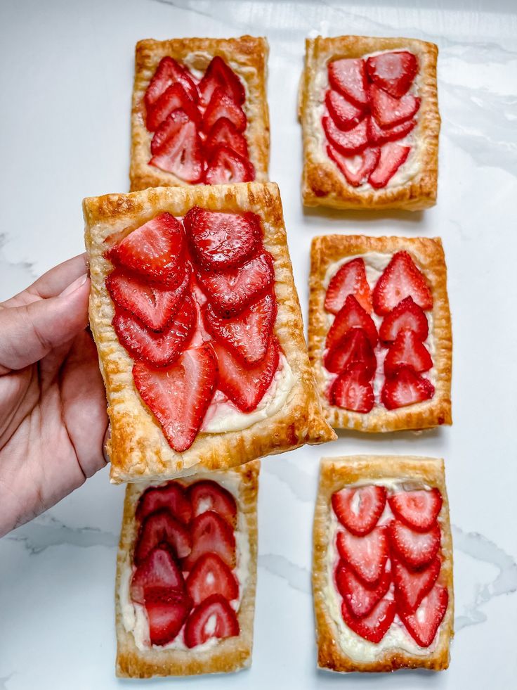 four pieces of pastry with strawberries arranged on top of each other in the shape of hearts