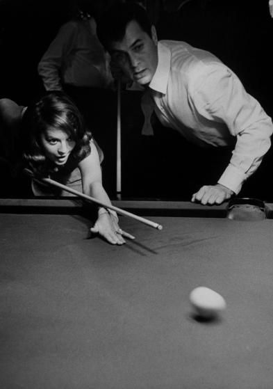 two men and a woman playing pool in an old black and white photo with one man leaning over the pool table