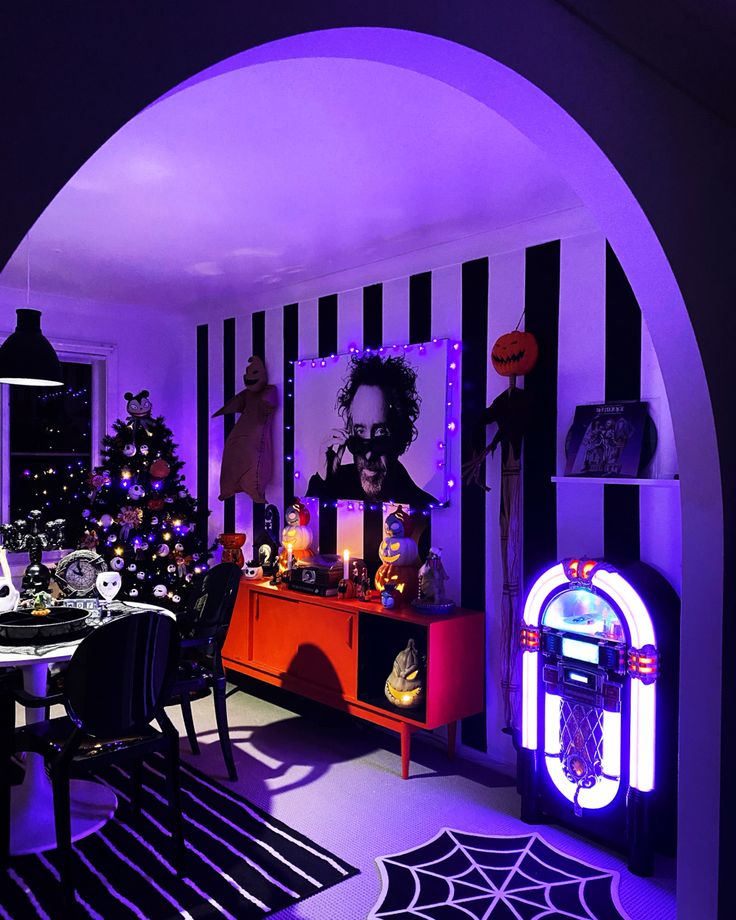 a halloween themed dining room with purple lighting and decorations on the walls, along with black and white striped walls