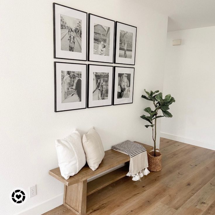 a wooden bench sitting in the middle of a living room next to a wall with pictures on it