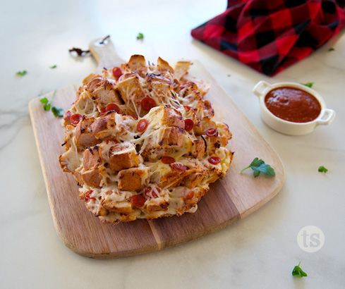 a pizza sitting on top of a wooden cutting board next to a bowl of sauce