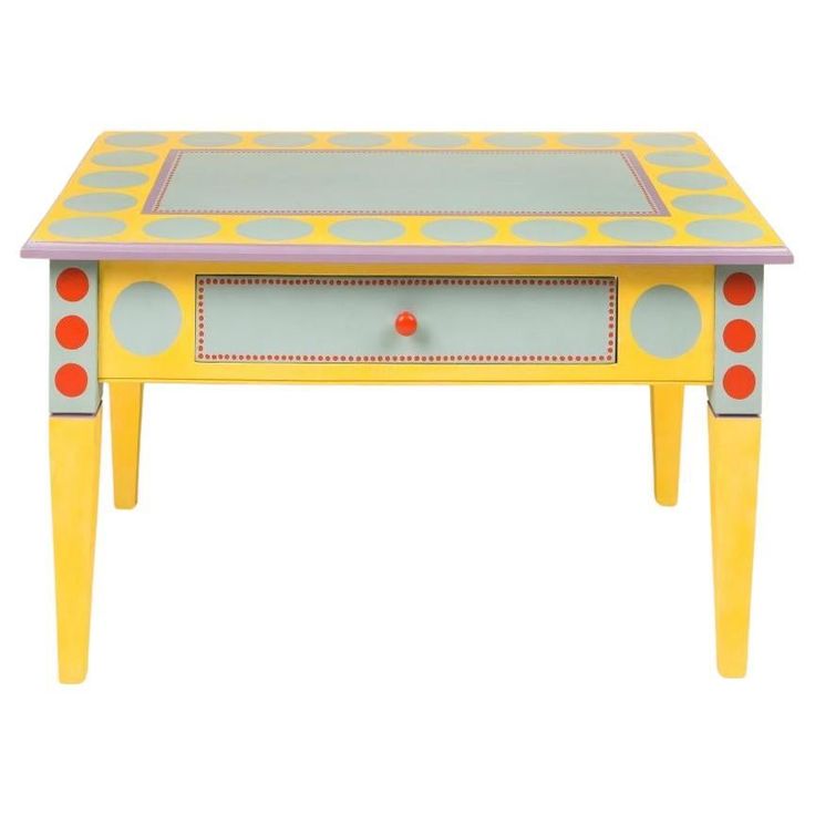 a yellow table with red and blue dots painted on the top, sitting in front of a white background