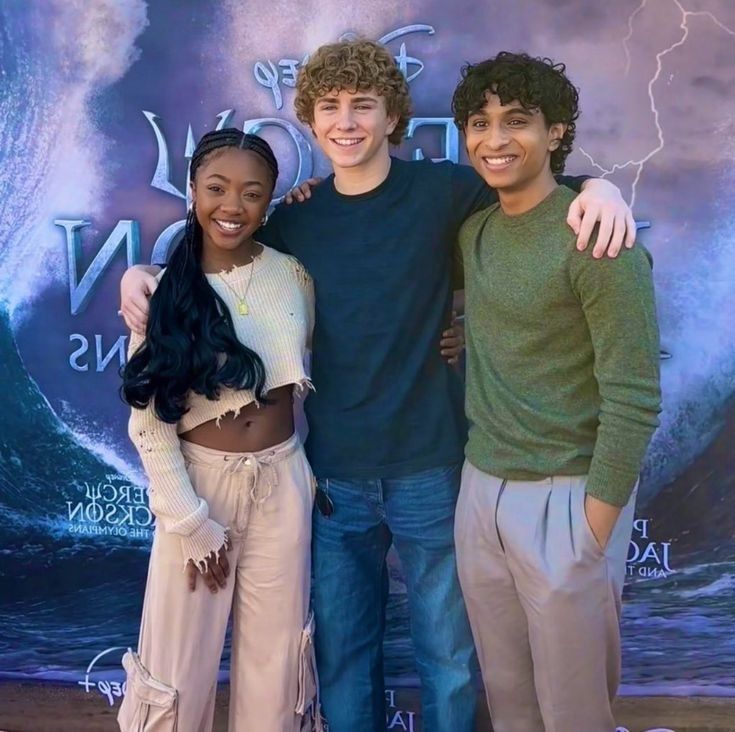 three people standing next to each other in front of a poster for disney's the lion king